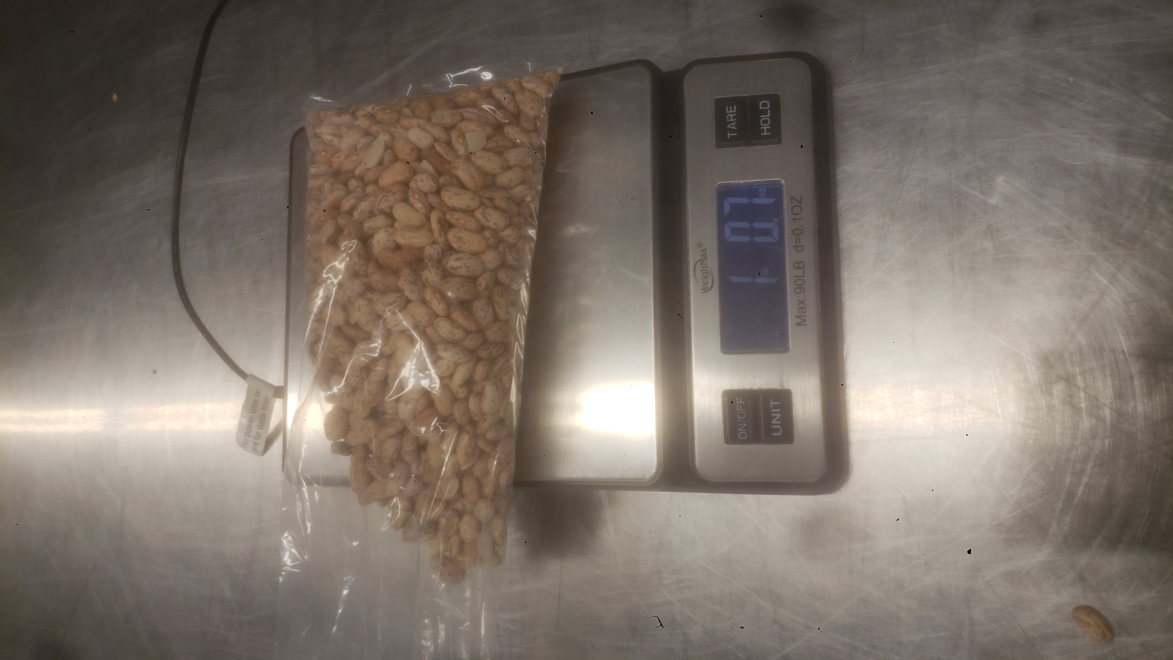 Bag of pinto beans on a weight scale that reads one pound and seven ounces.